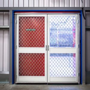 Pair of double action fly screen doors with diamond grille in a red-framed doorway
