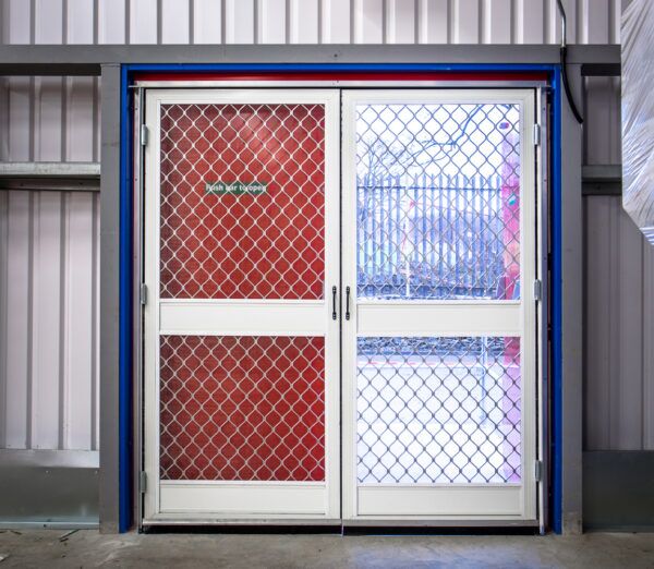Double fly screen door 2 way hinges Pair of double action fly screen doors with diamond grille in a red-framed doorway