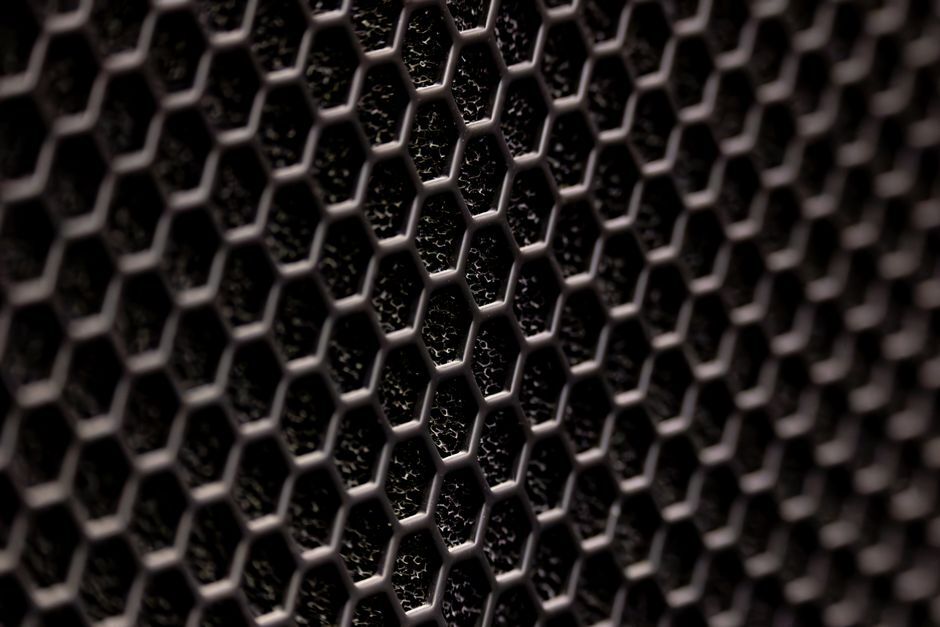 Detailed close-up of a dark hexagonal metal pattern with a textured surface.