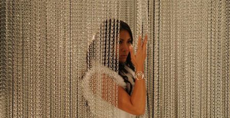 Woman parting an aluminium chain insect screen in a doorway