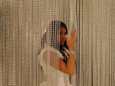 Woman parting an aluminium chain insect screen in a doorway