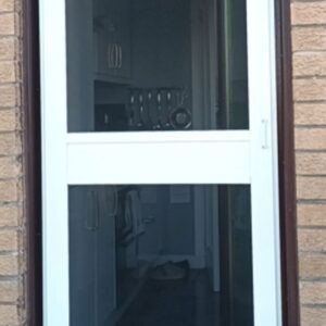 White pedestrian fly screen door with mid rail on a brick building