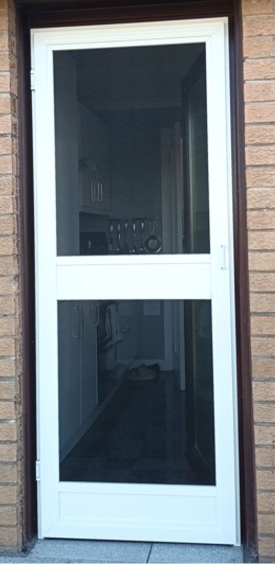 White pedestrian fly screen door with mid rail on a brick building