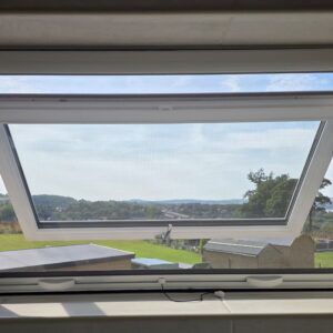 Roller fly screen fitted inside a top-hung window